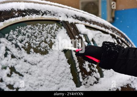 Entfernen von Schnee von der Windschutzscheibe des Autos. Reinigen Sie das Autofenster im Winter vom Schnee. Stockfoto