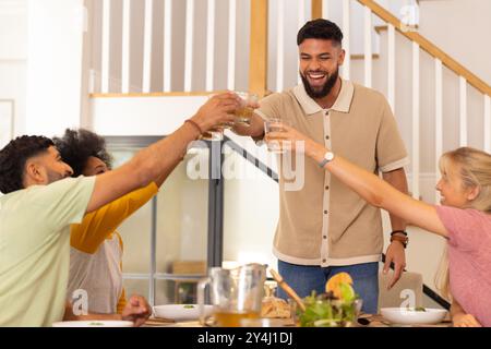 Freunde, die Getränke am Esstisch anstoßen, Essen genießen und gemeinsam feiern Stockfoto