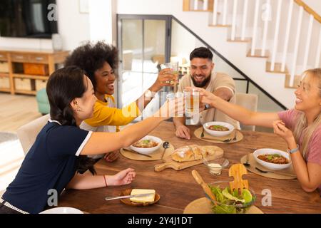 Freunde, die beim Abendessen mit Drinks anstoßen und gemeinsam zu Hause essen Stockfoto