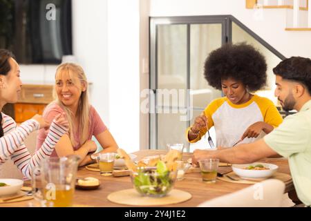 Essen Sie zusammen zu Mittag, eine Gruppe von jungen, vielfältigen Freunden, die zu Hause essen Stockfoto