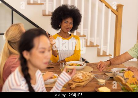 Essen Sie zusammen zu Mittag, eine Gruppe von jungen Freunden, die Essen am Tisch genießen Stockfoto