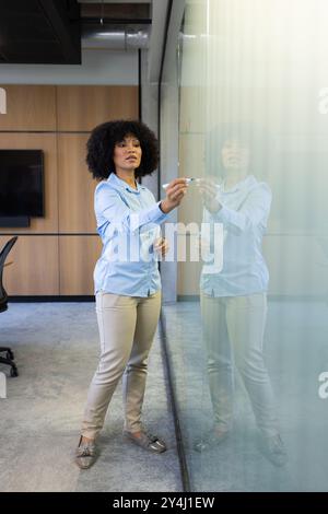 Schreiben auf Glasplatte, Geschäftsfrau präsentiert Ideen in modernem Büroumfeld Stockfoto