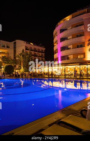 Alanya, Türkei - 17. September 2021: Ein wunderschön beleuchteter Hotelpool bei Nacht, umgeben von Liegestühlen und Palmen in Antalya, Türkei. Stockfoto