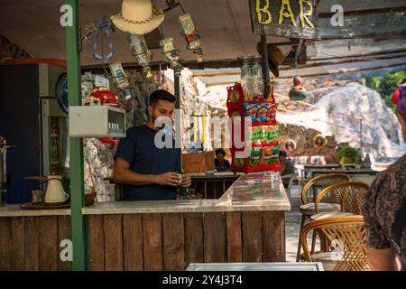 Alanya, Türkei - 17. September 2021: Ein Barkeeper bereitet einen Drink an einer gemütlichen Bar im Freien zu. Die rustikale Einrichtung mit Snacks sorgt für eine warme, einladende Atmosphäre Stockfoto