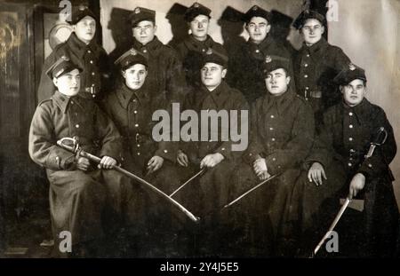 Vintage-Foto einer Gruppe polnischer uniformierter Soldaten, die für ein Foto posieren, das Schwerter in einem formellen Setting hält. Vorkriegspolen 1937 Stockfoto