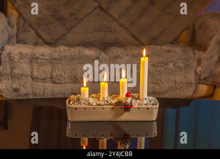 Weihnachtskerzenhalter mit vier beleuchteten Kerzen symbolisieren den vierten Advent in gemütlicher Einrichtung des Apartments. Stockfoto