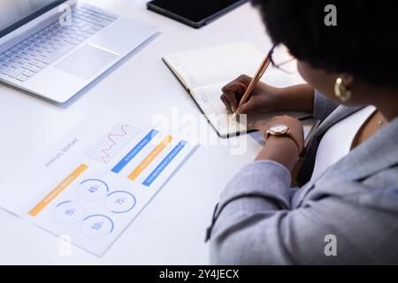 Schreiben in Notizblock, Geschäftsfrau analysiert Jahresbericht am Bürotisch Stockfoto