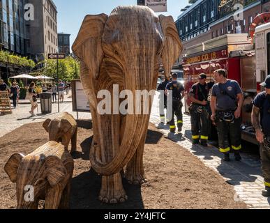 Mitglieder der FDNY sehen die öffentliche Kunstinstallation Great Elephant Migration im Meatpacking District in New York am Dienstag, den 10. September 2024. Die 100 Statuen wurden von der Coexistence Collective geschaffen, deren Mission es den Menschen ermöglicht, den Raum mit den prächtigen Kreaturen der Natur zu teilen. Die Elefanten wurden von indianischen Handwerkern aus der Lantana Camara, einer invasiven Pflanzenart, gebaut. Die Installation wird bis zum 20. Oktober ausgestellt. (©ÊRichard B. Levine) Stockfoto