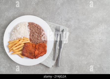 Milanesisches Rindfleisch, Reis, Bohnen und Pommes frites. Typisch brasilianisches Executive-Gericht auf Steinhintergrund mit Kopierraum. Stockfoto