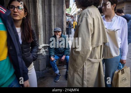 Ein älterer Mann, der vor einer Kirche in Barcelona sitzt, bittet um Gelder. Stockfoto