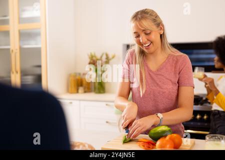 Gemüse hacken, junge Frau lächelt und Essen in der Küche mit verschiedenen Freunden zubereitet Stockfoto