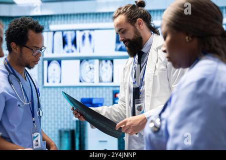 Radiologen und Spezialisten untersuchen Röntgenstrahlen und diskutieren medizinische Versorgung in einer Privatklinik. Team von qualifizierten Gesundheitsexperten, die zusammenarbeiten, um genaue Diagnose- und Behandlungsoptionen zu bieten. Stockfoto