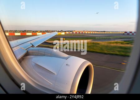 Wingview eines modernen Jet-Flugzeugs, das in der Abendsonne zum Start am Flughafen Amsterdam Schiphol fährt Stockfoto