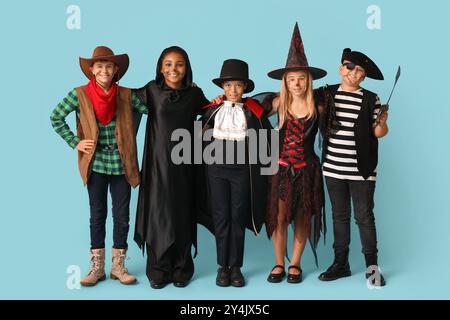 Niedliche glückliche Kinder in verschiedenen Kostümen für Halloween-Party auf blauem Hintergrund gekleidet Stockfoto