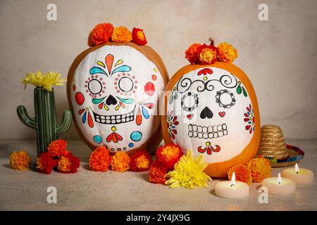 Kürbisse mit bemalten Schädeln, brennenden Kerzen, Blumen und Dekor auf hellem Hintergrund. El Dia de Muertos Stockfoto