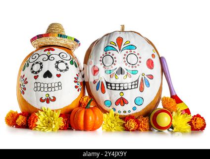 Kürbisse mit bemalten Schädeln, Mini-Sombrero, Maracas und Blumen auf weißem Hintergrund. El Dia de Muertos Stockfoto