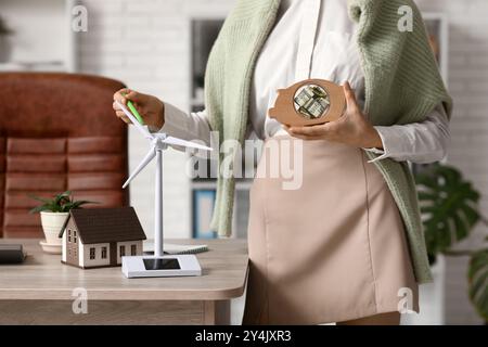 Ingenieurin mit Schweinebank und Windkraftanlagenmodell auf dem Tisch im Büro Stockfoto