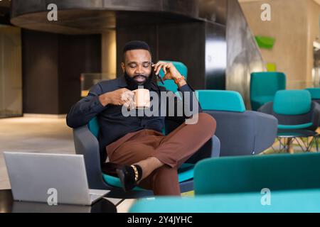 Telefonieren und Kaffee trinken, Geschäftsmann arbeitet am Laptop im Büro Stockfoto