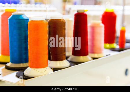 Spulen aus farbigem Faden auf einer industriellen Nähmaschine. Bekleidungsindustrie Stockfoto