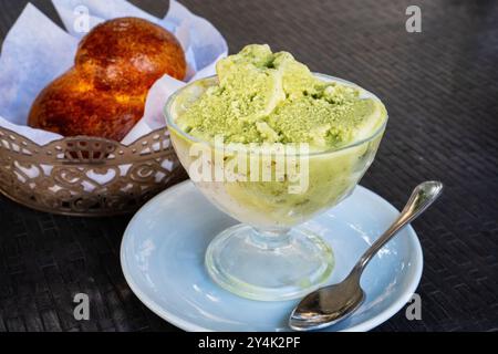 Authentische sizilianische Pistaziengranita, serviert in einer Glasschale, begleitet von traditioneller Mandel-Brioche. Dieses erfrischende italienische Gefrierdessert ist ein Knall Stockfoto