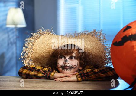 Süßer Junge, der nachts drinnen wie Vogelscheuche gekleidet ist. Halloween-Feier Stockfoto