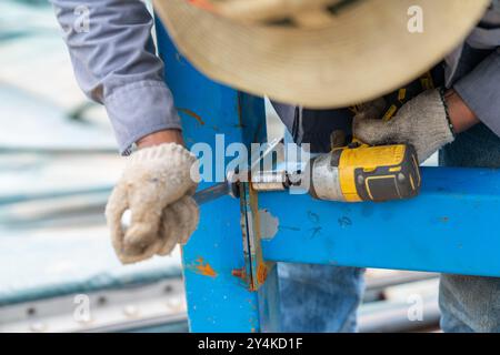 Arbeiter verwenden Sie eine Akku-Blockschraube und einen Schraubenschlüssel. Entfernen Sie die Mutter des Fachs ab Werk. Stockfoto