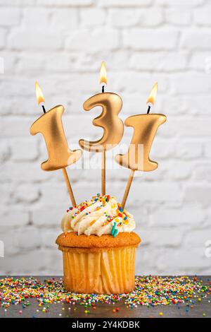 Goldene Geburtstagskerze Nummer 131 mit Cupcake - weißer Block Wand Hintergrund Stockfoto