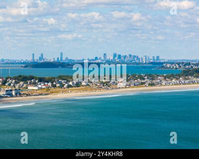 Der historische Nantasket Beach aus der Vogelperspektive mit der Skyline der modernen Stadt Boston, einschließlich Finanzviertel und Back Bay im Hintergrund, aus dem Schlepptau gesehen Stockfoto