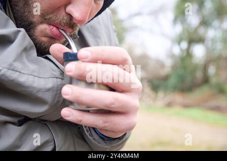 Nahaufnahme eines jungen argentinischen Mannes, der an einem kühlen Wintermorgen ein traditionelles Heißgetränk trinkt. Komposition mit Kopierraum. Stockfoto