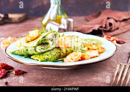 Grüne Pfannkuchen in Nahaufnahme mit Garnelenfüllung und Käse auf dunklem Hintergrund Stockfoto