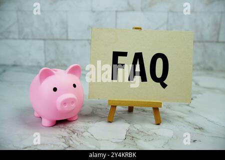 FAQ-Text auf Papierkarte mit Schweinespar auf Marmorhintergrund geschrieben Stockfoto