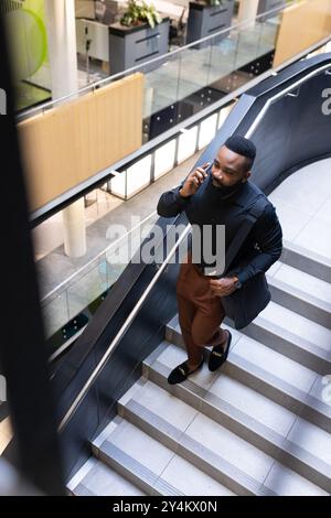 Treppen hinauf gehen, Geschäftsmann mit Smartphone reden und Schultertasche tragen Stockfoto