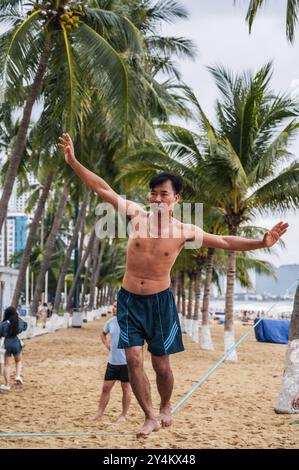 Ein asiatischer akrobat läuft an einem gestreckten Seil am Strand entlang, um Slackline zu trainieren. Nha Trang, Vietnam - 25. Juli 2024 Stockfoto