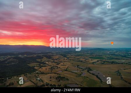 Blick aus der Vogelperspektive auf das Yarra Valley bei Sonnenaufgang (ein Heißluftballon in Sicht), aufgenommen von einer Fahrt im Heißluftballon, Victoria, Australien Stockfoto