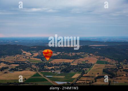 Blick aus der Vogelperspektive auf das Yarra Valley bei Sonnenaufgang (ein Heißluftballon in Sicht), aufgenommen von einer Fahrt im Heißluftballon, Victoria, Australien Stockfoto