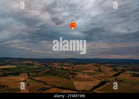 Blick aus der Vogelperspektive auf das Yarra Valley bei Sonnenaufgang (mit mehreren Heißluftballons in Sicht), aufgenommen von der Heißluftballonfahrt, Victoria, Australien Stockfoto