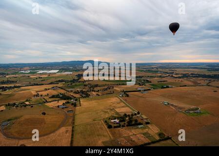 Blick aus der Vogelperspektive auf das Yarra Valley bei Sonnenaufgang (ein Heißluftballon in Sicht), aufgenommen von einer Fahrt im Heißluftballon, Victoria, Australien Stockfoto