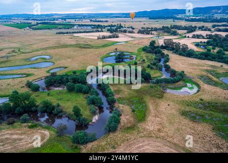 Blick aus der Vogelperspektive auf das Yarra Valley bei Sonnenaufgang (ein Heißluftballon in Sicht), aufgenommen von einer Fahrt im Heißluftballon, Victoria, Australien Stockfoto