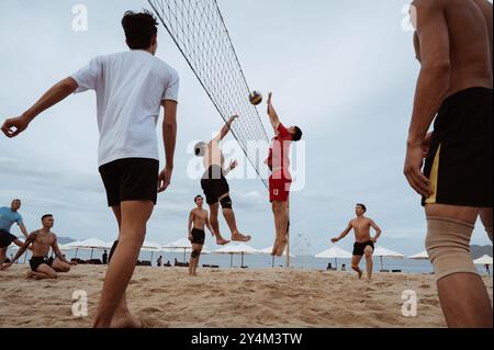 Asiatische vietnamesische Spieler spielen Beachvolleyball an einem Sandstrand am Meer während des Sommertages in Nha Trang. Nha Trang, Vietnam - 21. Juli 2024 Stockfoto