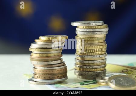 Stapel von Münzen und Euro-Banknoten auf weißem Tisch, Nahaufnahme Stockfoto