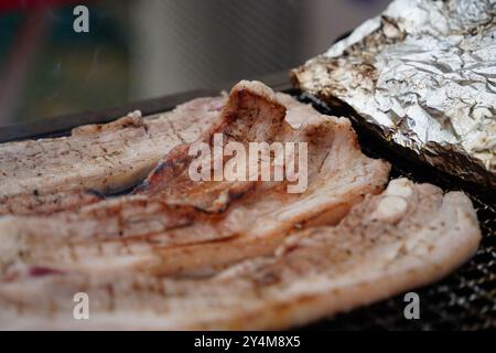 Nahaufnahme des Schweinebauchs, der auf einem Holzkohlegrill gegrillt wird. Stockfoto