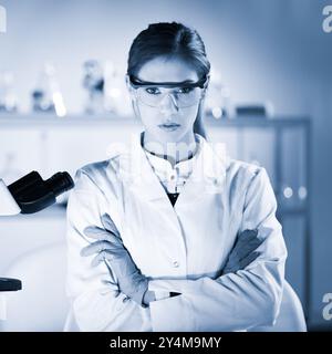 Porträt einer attraktiven, jungen, selbstbewussten weiblichen Gesundheitsfachkraft in ihrem Arbeitsumfeld. Blau getöntes Schwarz-Weiß-Bild. Stockfoto