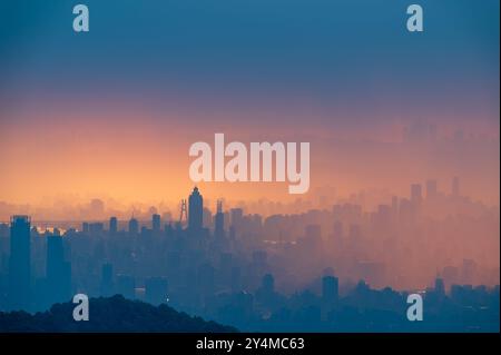 Ein Panoramablick auf die Skyline von Taipei City nach dem Regen. Die untergehende Sonne wirft ein warmes Leuchten über die Stadtlandschaft und schafft dramatische Silhouetten der Skyscra Stockfoto