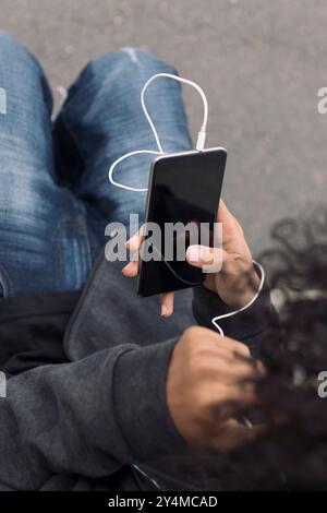 Nicht erkennbarer Teenager, der Musik auf dem Telefon hört Stockfoto