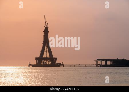 Die majestätische Silhouette der Tamsui-Brücke im Bau ist in den goldenen Tönen des Sonnenuntergangs getaucht. Die unvollendete Struktur steht hoch gegen ein V Stockfoto