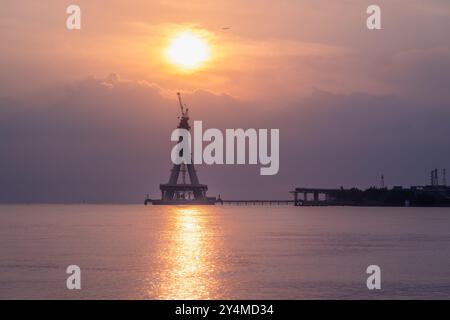 Die majestätische Silhouette der Tamsui-Brücke im Bau ist in den goldenen Tönen des Sonnenuntergangs getaucht. Die unvollendete Struktur steht hoch gegen ein V Stockfoto