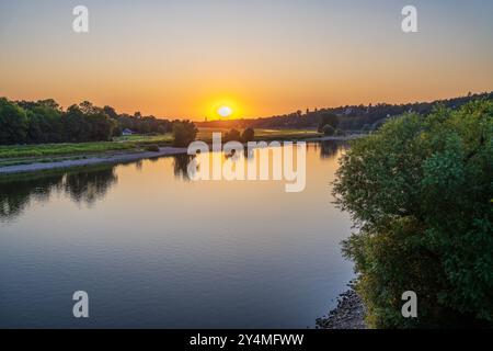 Sonnenuntergang auf dem Fluss. Gelbe Sonnenscheibe sinkt. fluss bei Sonnenuntergang. Leute, die am Ufer des Flusses Elba sitzen. Dresden. Stockfoto