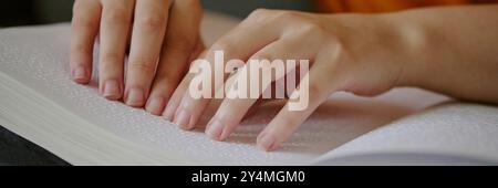 Website-Banner mit nicht erkennbaren weiblichen Händen, die Punkte auf der Seite des Braille-Buches berühren Stockfoto