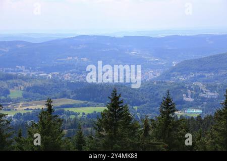 Blick auf das Tal und die Stadt Suhl, umgeben von bewaldeten Hügeln und entfernten sanften Bergen. Stockfoto