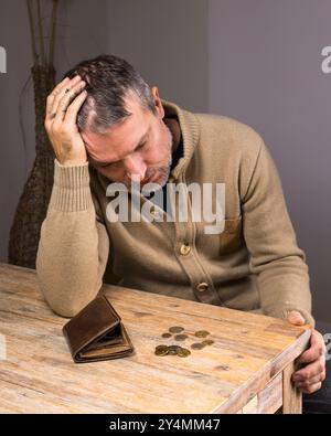 Ein Mann, der auf eine leere Brieftasche mit kleinen Münzen blickt. Armer Mann ohne Geld in der Brieftasche. Finanzielle Schwierigkeiten. Geringes Einkommen für Menschen mittleren Alters. Arbeitsplatzverlust. Po Stockfoto